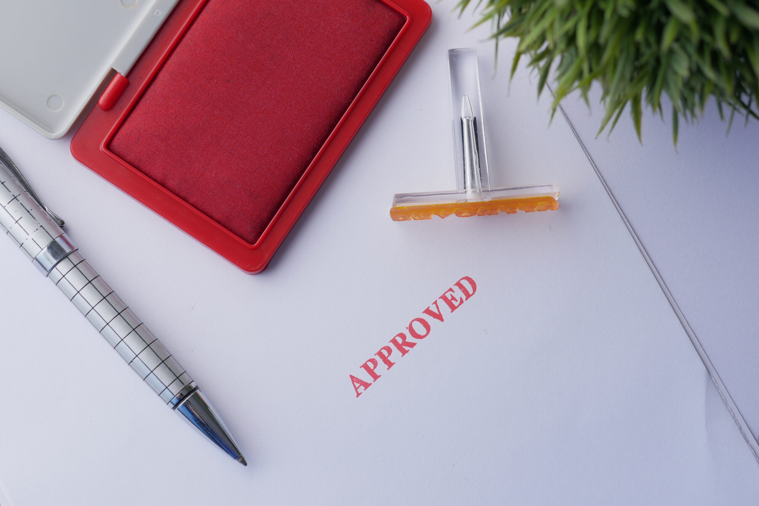 Close-up of an approved financing document with a red ink stamp and silver pen